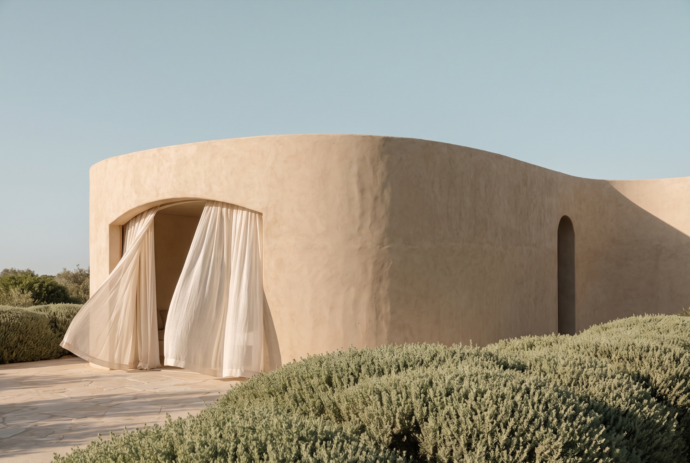 Clay-plaster retreat building with linen curtains moving in the breeze